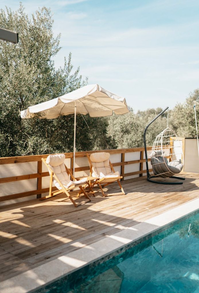 chairs-by-a-swimming-pool-19135440 Elegant outdoor terrace in Muğla, Türkiye featuring pool, chairs, and umbrella.